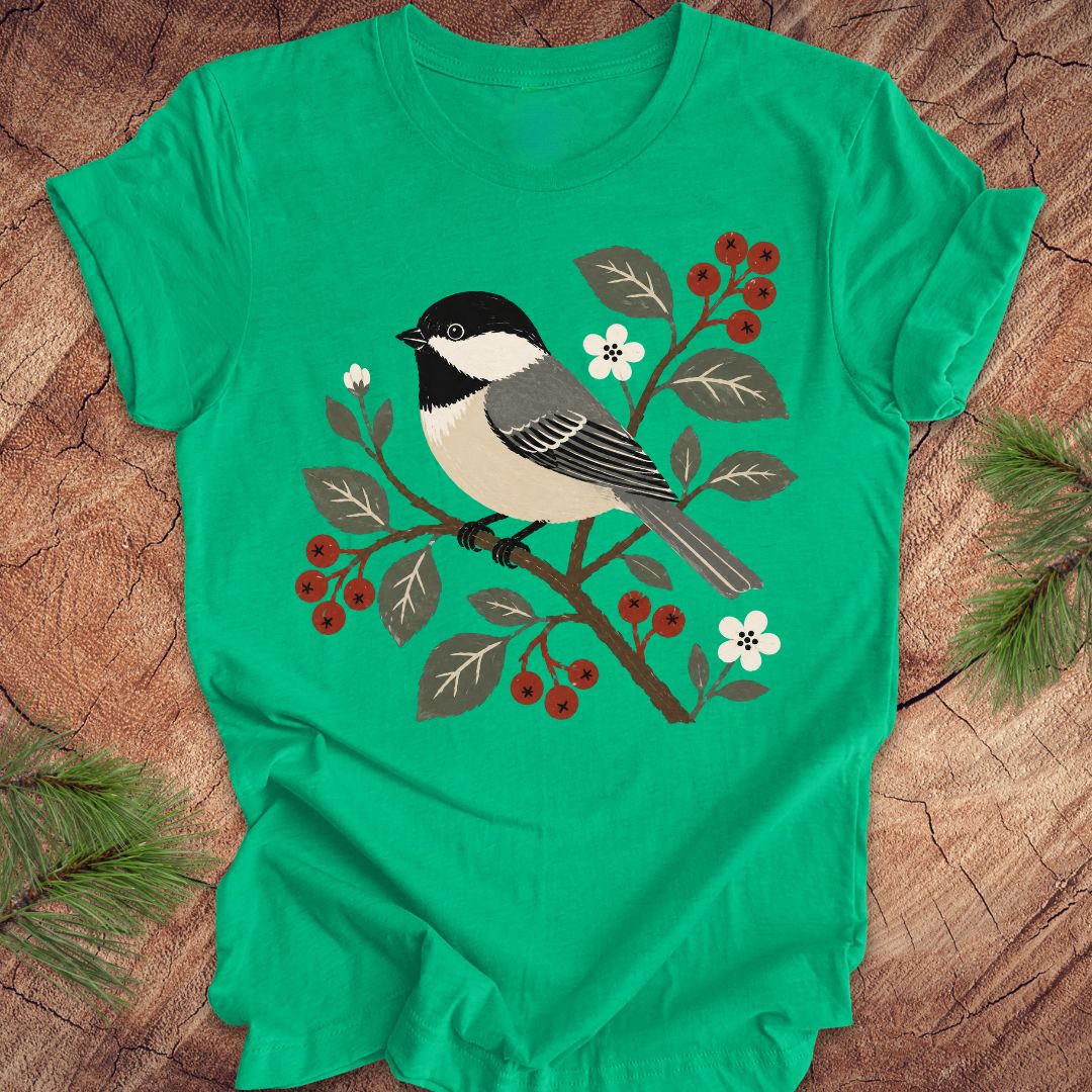 Green t-shirt with a chickadee design on a wooden surface