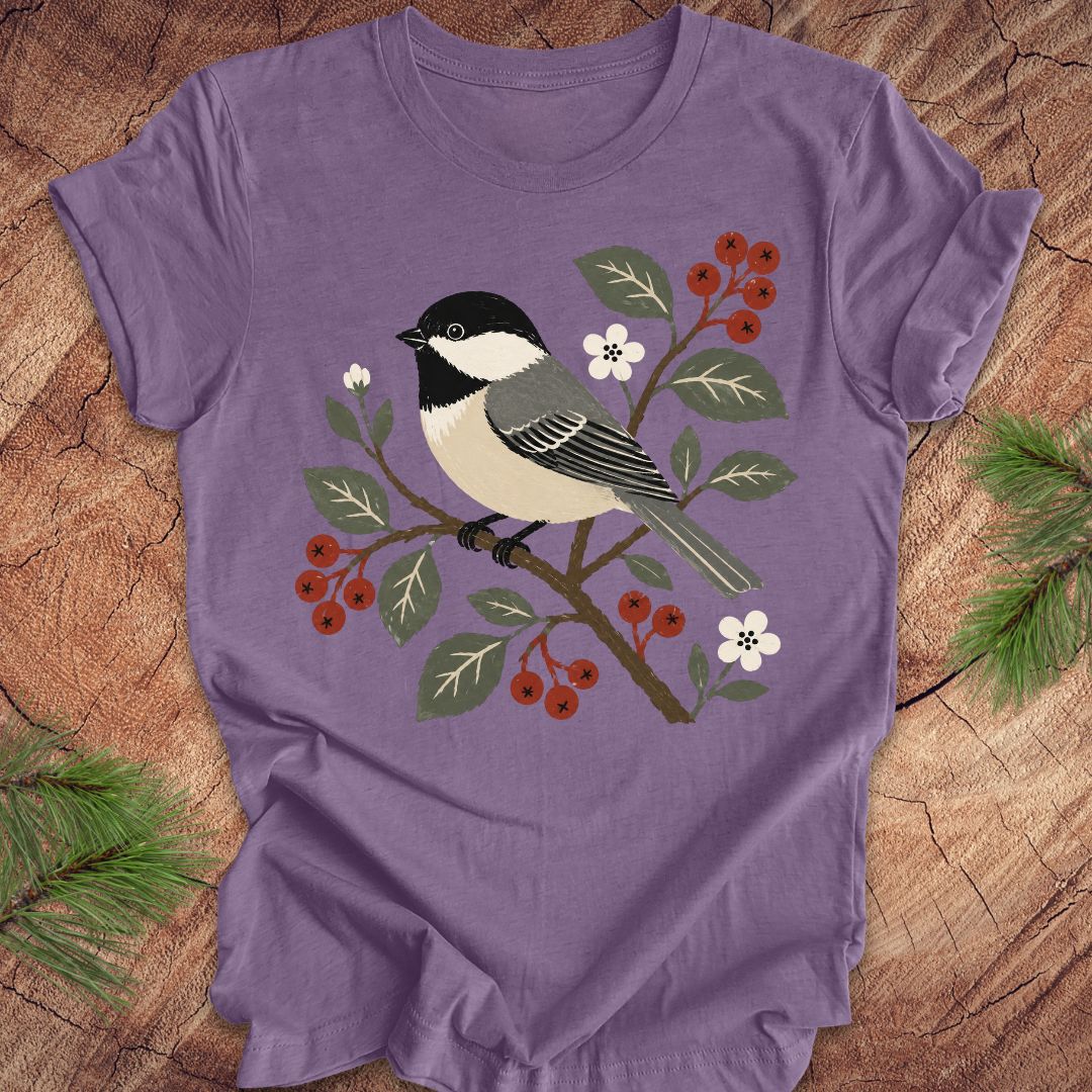 Purple t-shirt with a chickadee design on a wooden surface