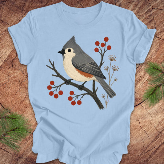 Blue t-shirt with a titmouse and berries design on a wood background.