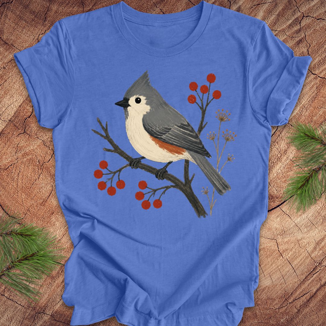 Blue t-shirt with a titmouse and berries design on a wood background.