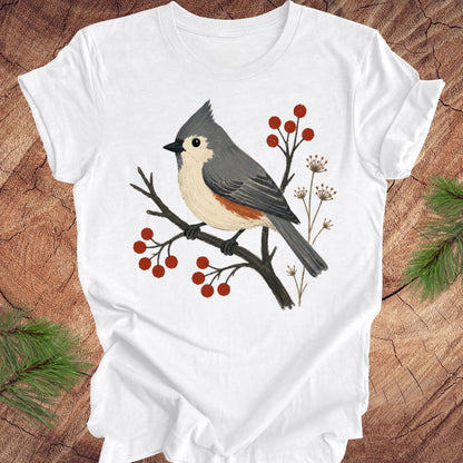 White t-shirt with a titmouse and berries design on a wood background.
