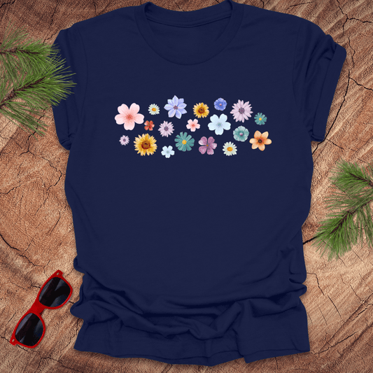 Navy blue t-shirt with colorful floral design on a wooden surface with sunglasses and greenery.