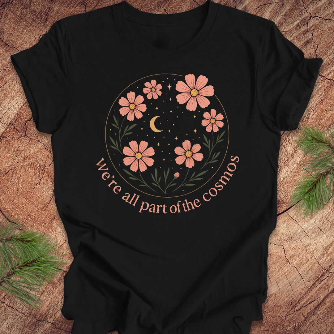 Black t-shirt with moon and stars and text "we're all part of the cosmos" on a wood background.