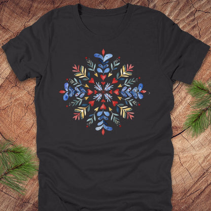 Dark grey t-shirt with a colorful snowflake and floral design on a wooden surface