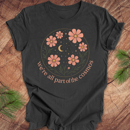 Gray t-shirt with moon and stars and text "we're all part of the cosmos" on a wood background.