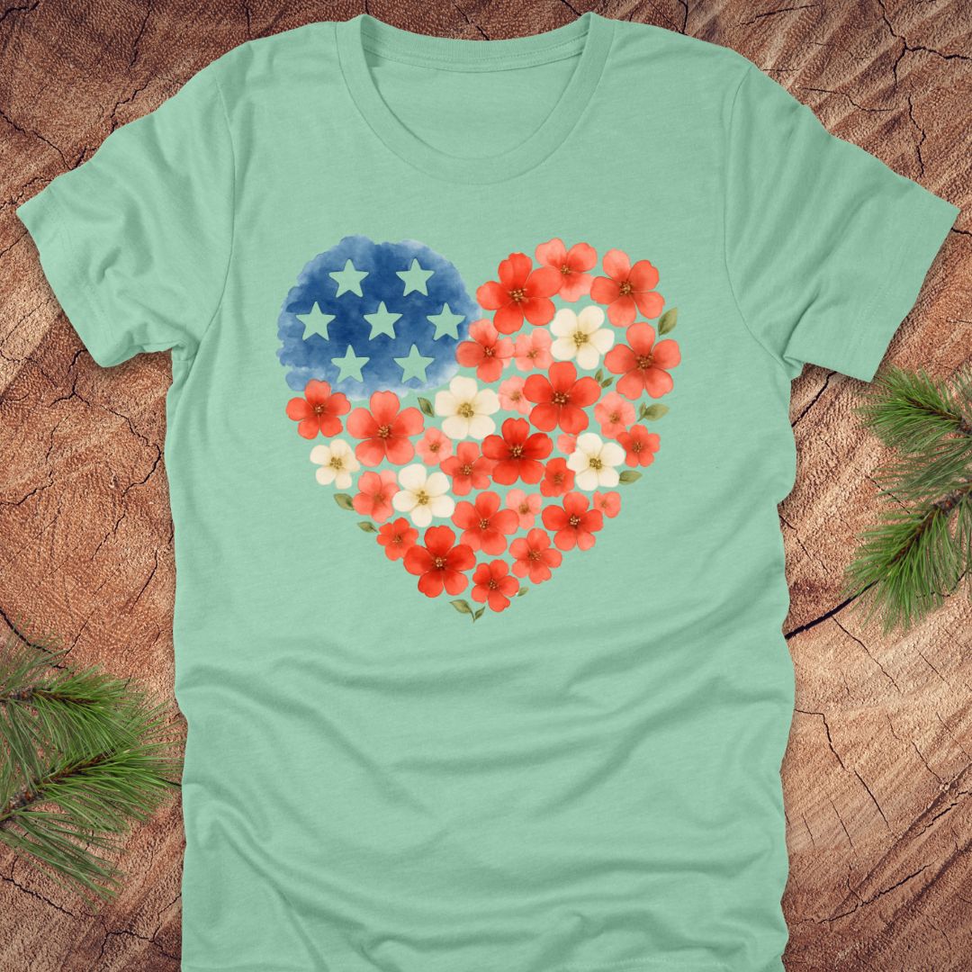 Mint green t-shirt with a heart-shaped design featuring red, white and blue flowers and stars on a wooden surface.