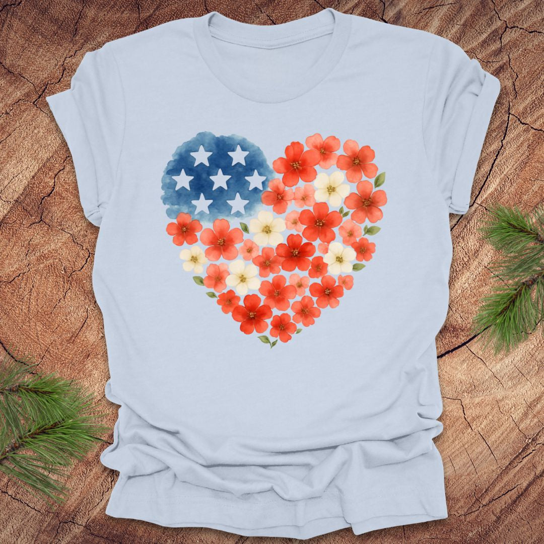 Light blue t-shirt with a heart-shaped design featuring red, white and blue flowers and stars on a wooden surface.