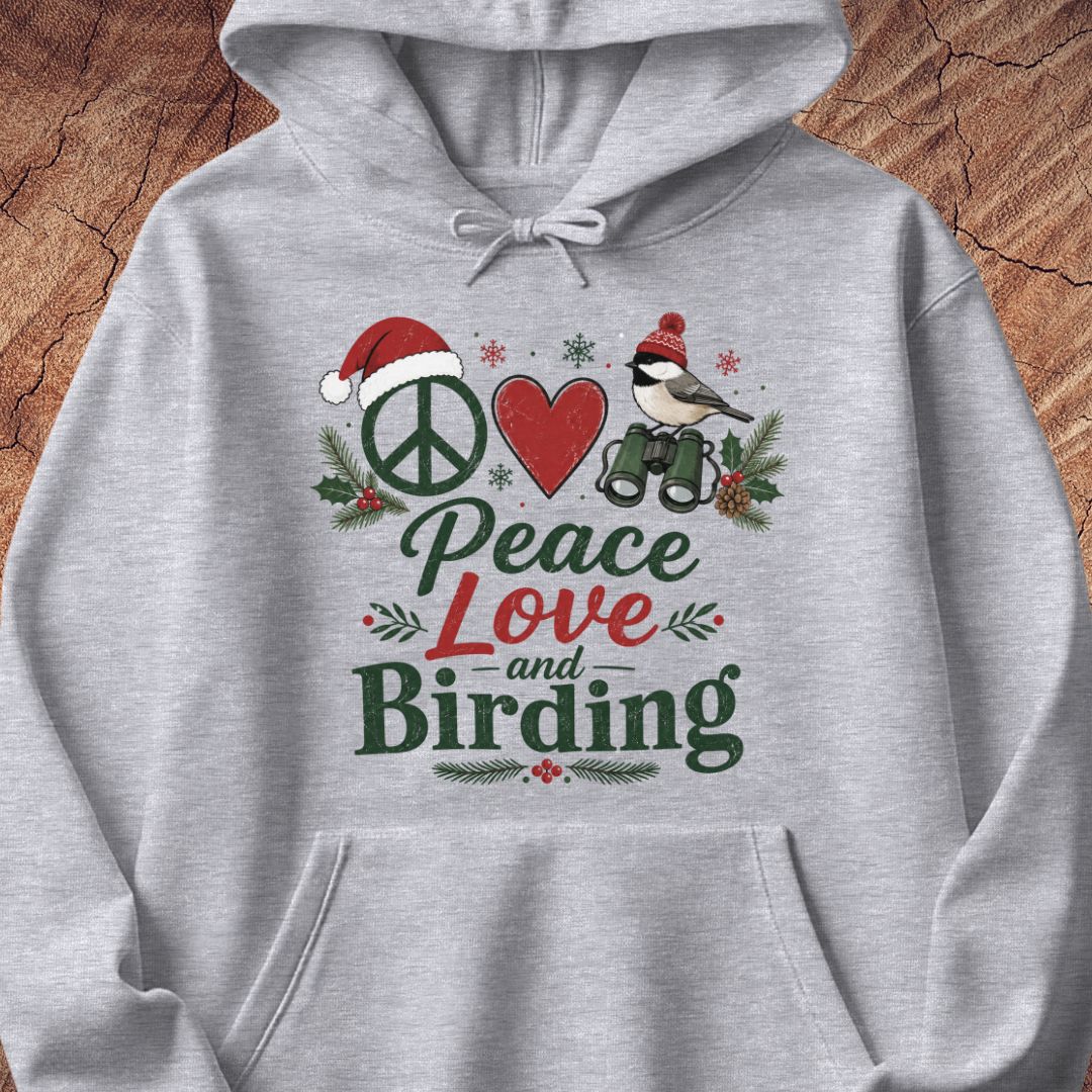 A light gray heather pullover hoodie with a festive Christmas-themed graphic on the chest. The graphic features a peace sign wearing a Santa hat, a red heart, a bird with binoculars, holly leaves, and the text 'Peace Love and Birding' in green and red lettering.
