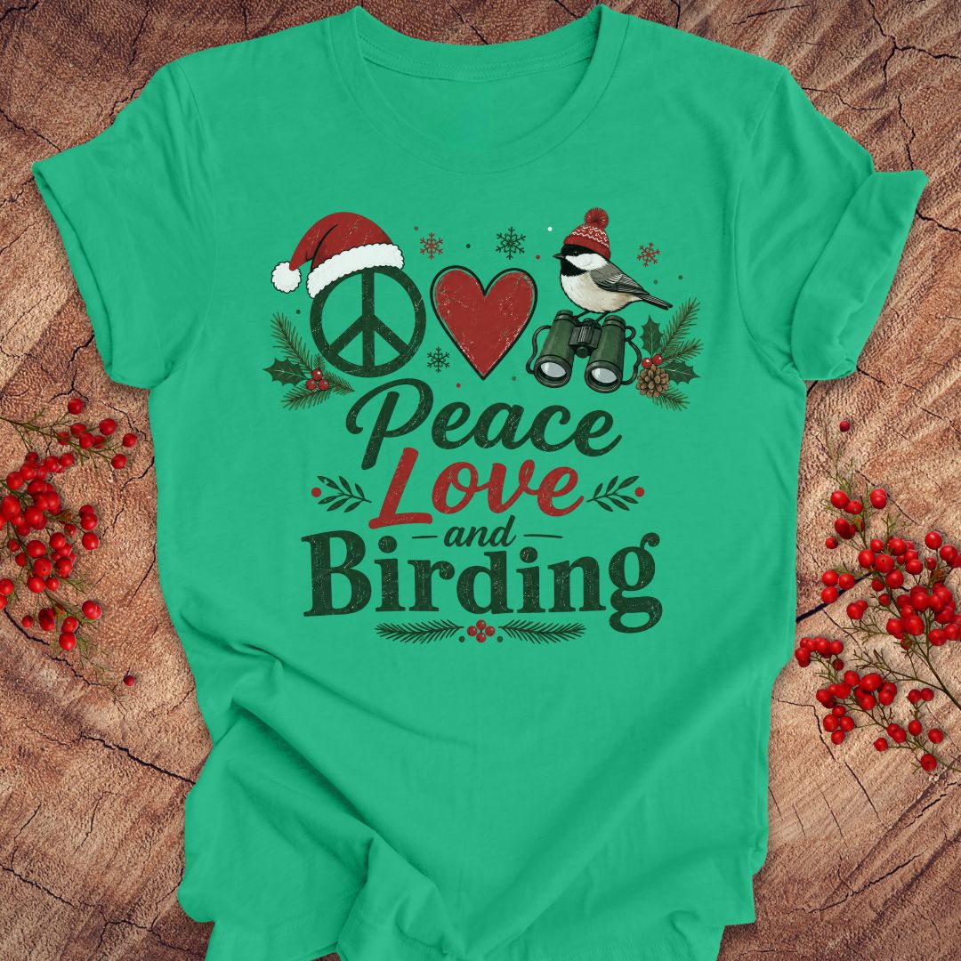 A bright green short-sleeve t-shirt with a festive Christmas-themed graphic reading 'Peace Love and Birding'. The graphic features a peace sign with a Santa hat, a red heart, a bird with binoculars, and holiday accents, displayed on a rustic wood background with red berries.