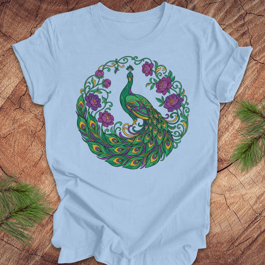 Light blue t-shirt with a peacock and flowers design on a wooden surface