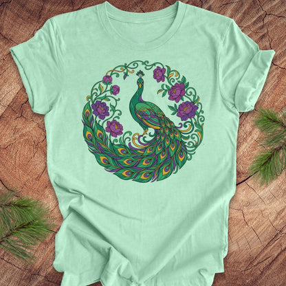 Mint green t-shirt with a peacock and flowers design on a wooden surface