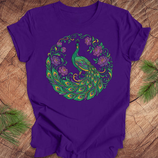 Purple t-shirt with a peacock and flowers design on a wooden surface