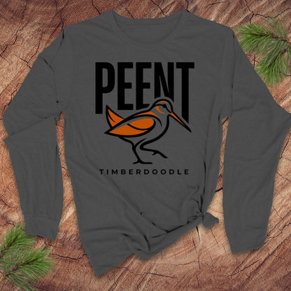 Gray long sleeve tshirt with 'PEENT TIMBERDOODLE' design on a wooden surface with pine branches.