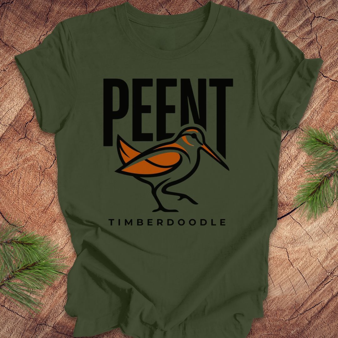 Green t-shirt with 'PEENT' and 'TIMBERDOODLE' woodcock design on a wooden surface.