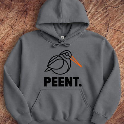 A dark gray pullover hoodie laid flat on a textured wood background. The hoodie features a minimalist black line art graphic of a bird with a bright orange beak, above the word 'PEENT.