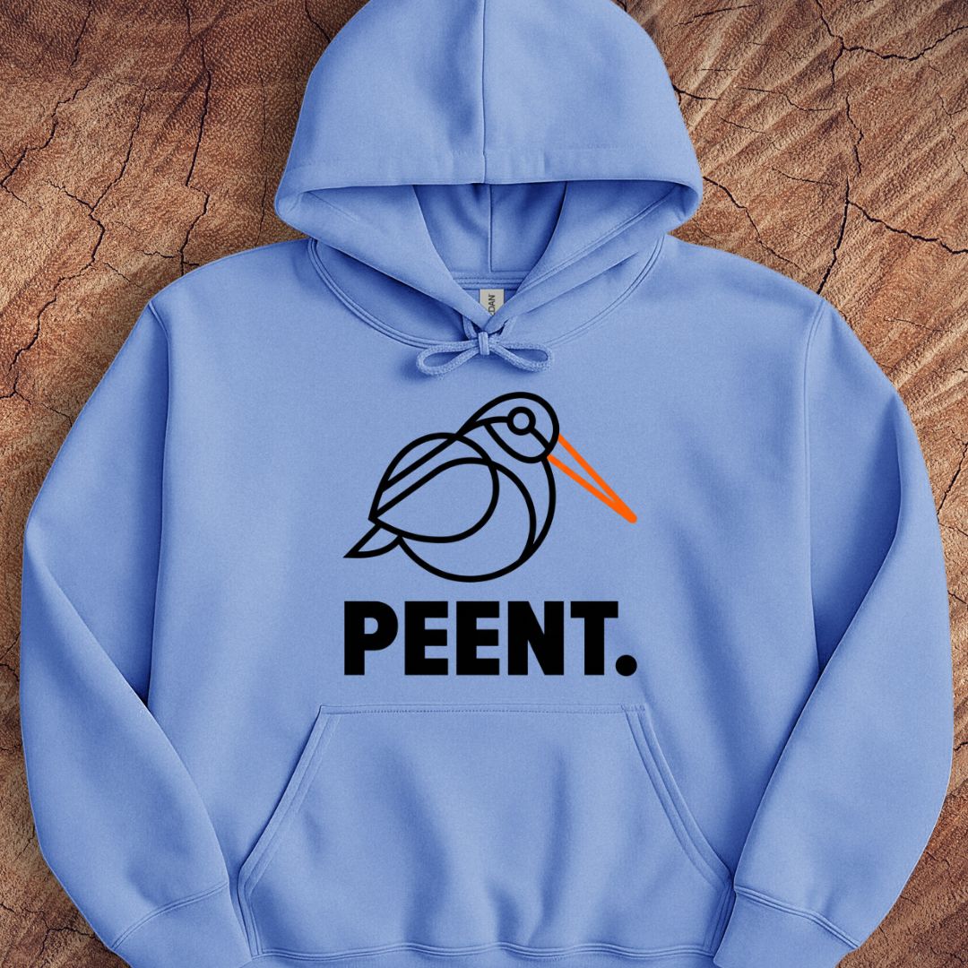 A light blue pullover hoodie laid flat on a textured wood background, featuring a black line-art bird graphic with an orange beak and the word 'PEENT.' in bold black letters below.