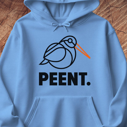 A light blue hoodie laid flat on a rustic wood background, featuring a black line-art bird graphic with an orange beak and the word 'PEENT.' in bold black letters below.