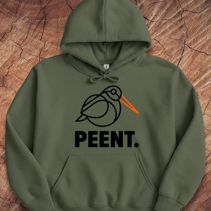 An olive green pullover hoodie with a graphic of a stylized black bird with an orange beak and the word 'PEENT.' printed below in black, laid flat on a textured brown wood background.
