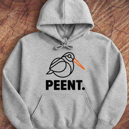 A light gray heather pullover hoodie laid flat on a textured brown wood background. The hoodie features a black line art graphic of a bird with a bright orange beak, above the word 'PEENT.