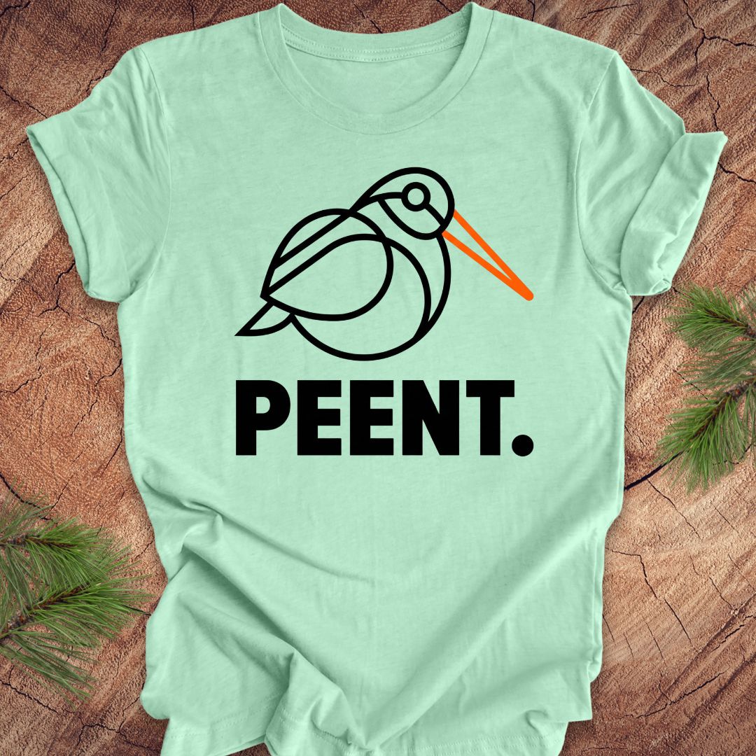 Mint green t-shirt with a woodcock graphic and 'PEENT.' text on a wooden surface.
