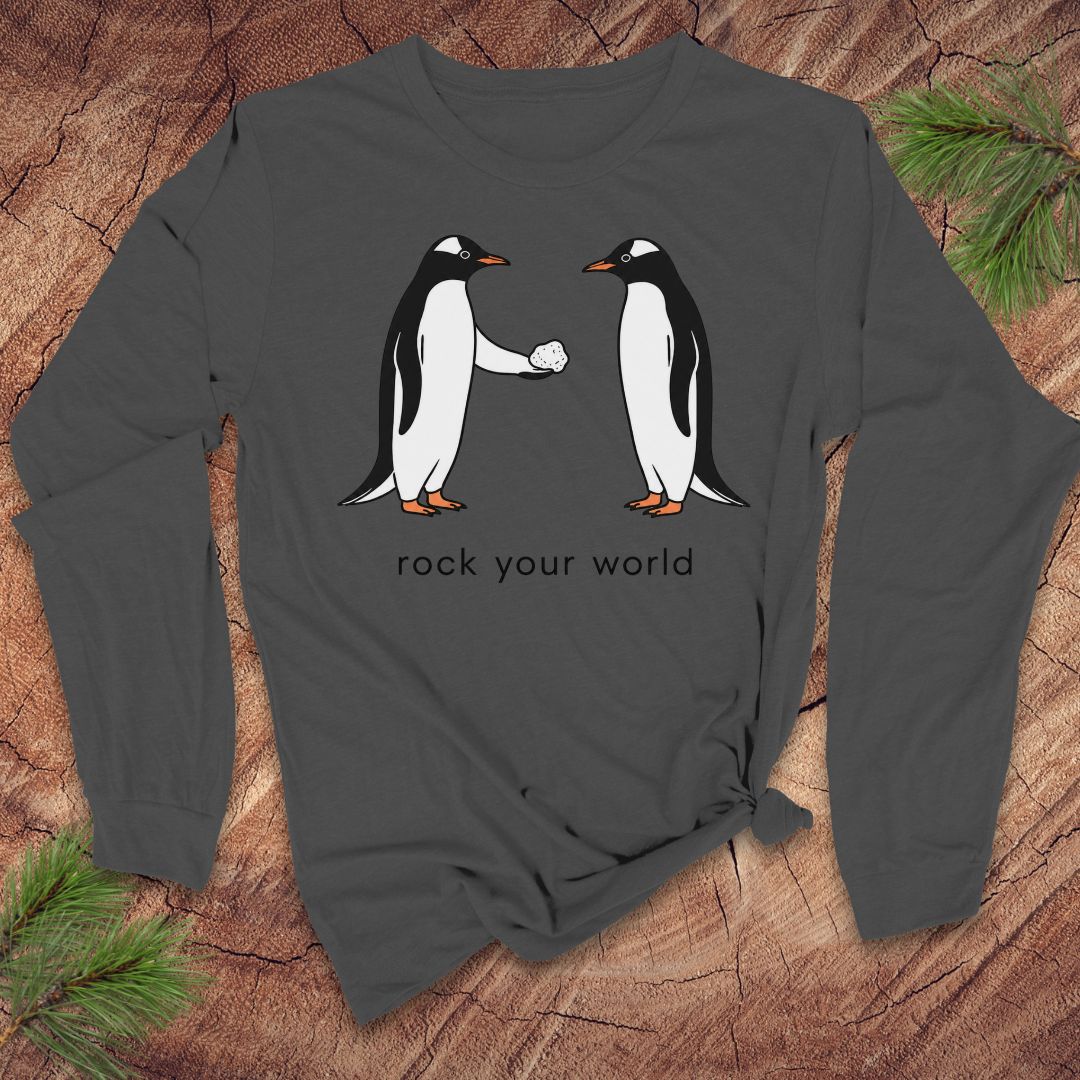 Gray long-sleeve t-shirt with penguins and text 'rock your world' on a wood background.