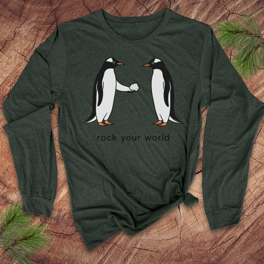 Green long-sleeve t-shirt with penguins and text 'rock your world' on a wood background.