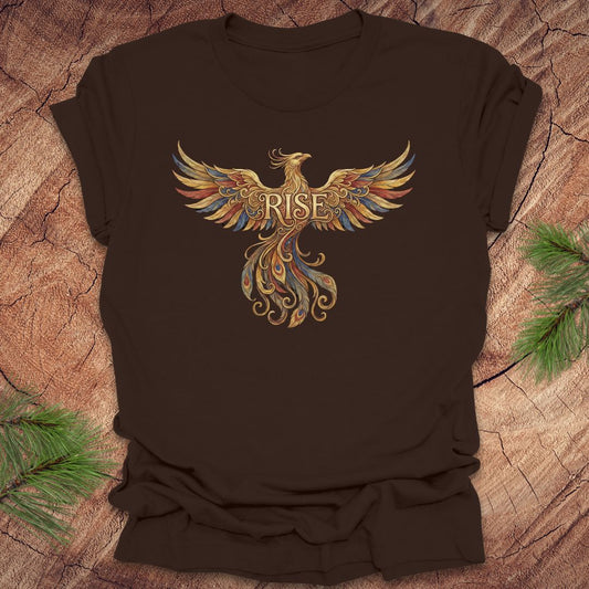 Brown t-shirt with a colorful phoenix design and 'RISE' text on a wooden surface.