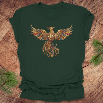 Green t-shirt with a phoenix design and 'RISE' text on a wooden surface.