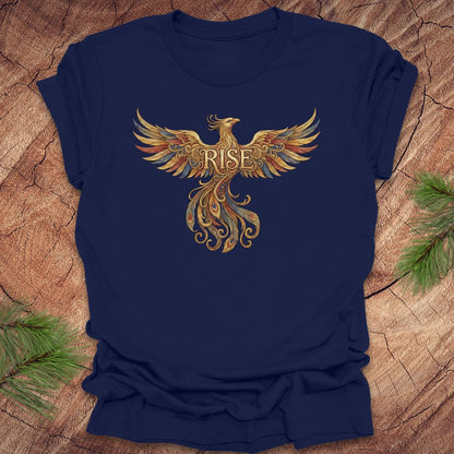 Navy blue t-shirt with a colorful phoenix design and 'RISE' text on a wooden surface.