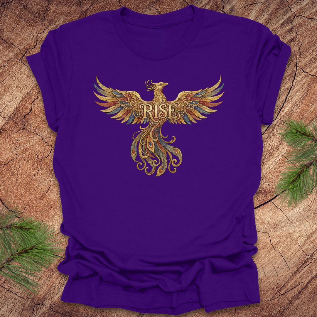 Purple t-shirt with a colorful phoenix design and 'RISE' text on a wooden surface.