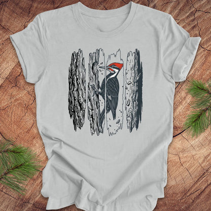 Gray t-shirt with a woodpecker design on a wooden surface