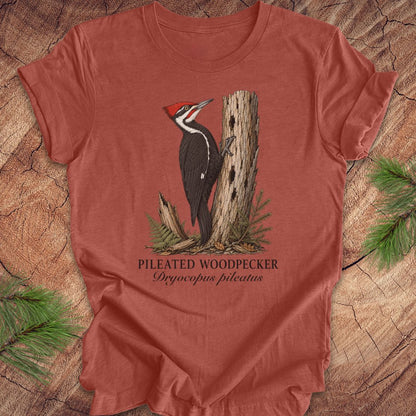 Red t-shirt with a pileated woodpecker graphic on a wooden surface