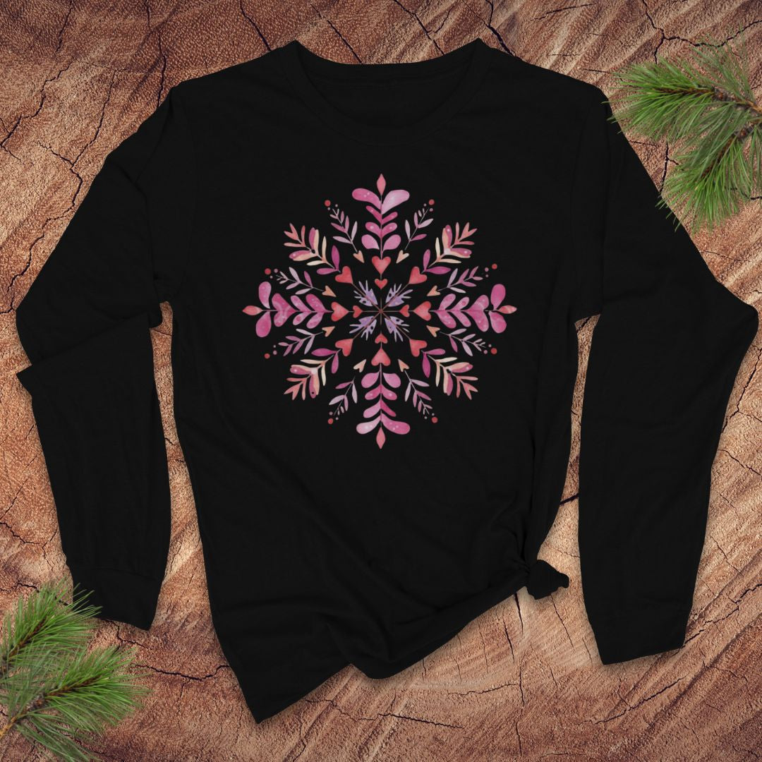 Black long-sleeve shirt with pink hearts and floral snowflake design on a wooden surface