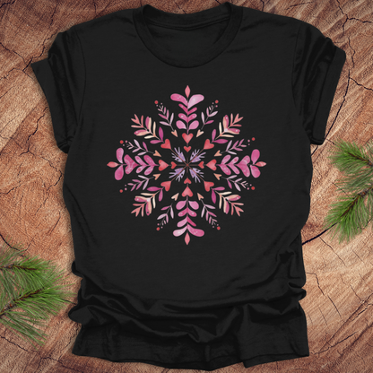 Black t-shirt with pinkhearts and floral snowflake design on a wooden surface
