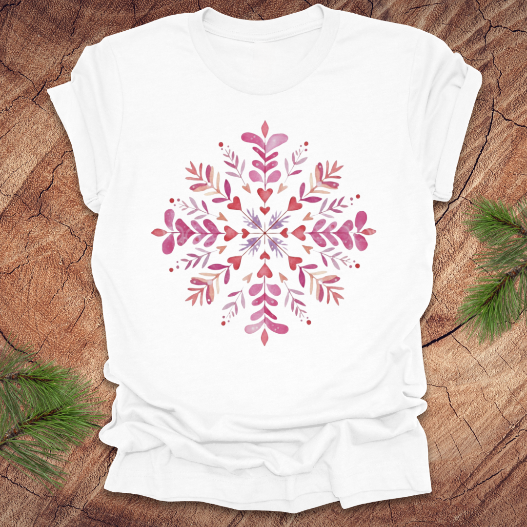 White t-shirt with pinkhearts and floral snowflake design on a wooden surface