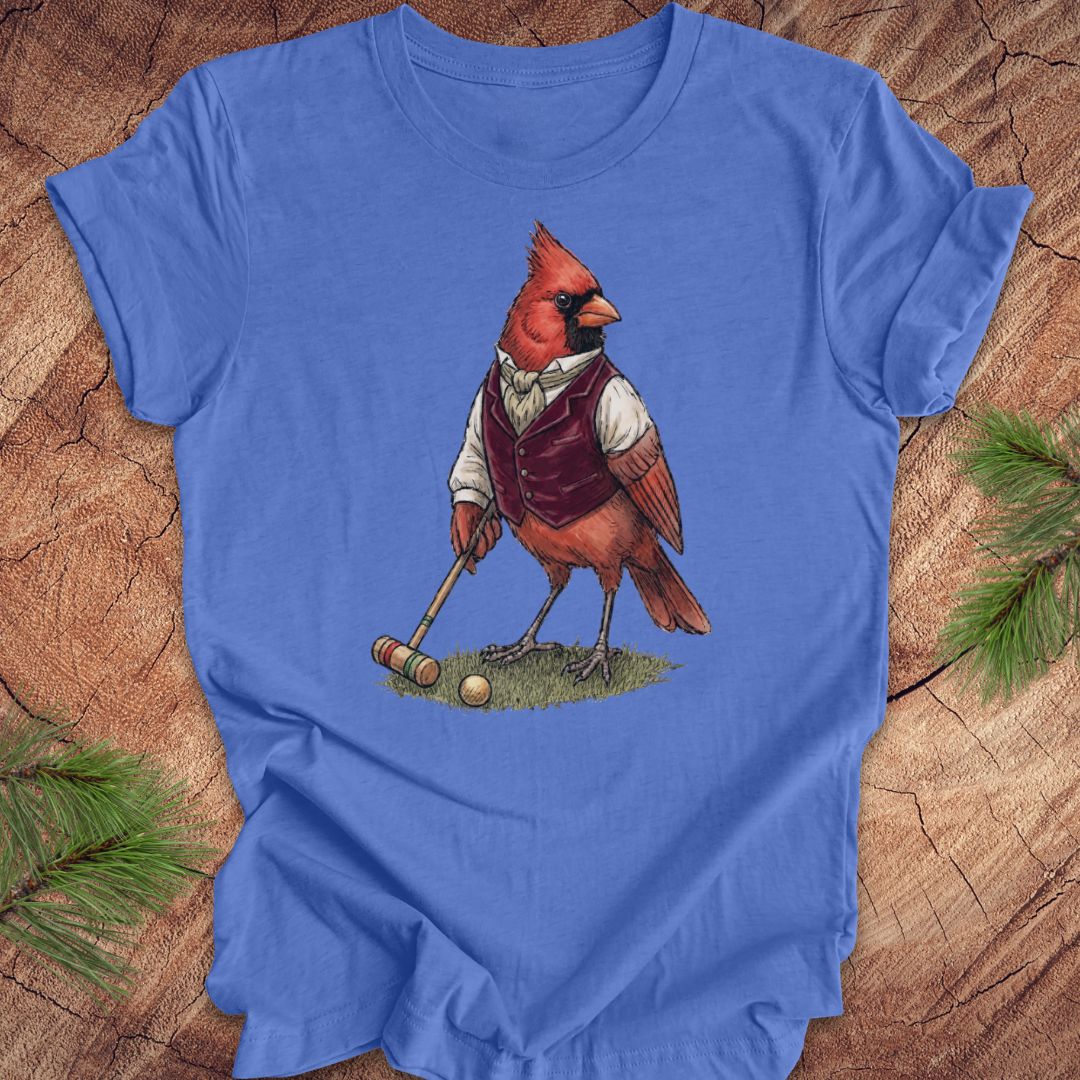 Blue t-shirt with a cardinal playing croquet design on a wooden surface.