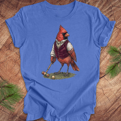 Blue t-shirt with a cardinal playing croquet design on a wooden surface.