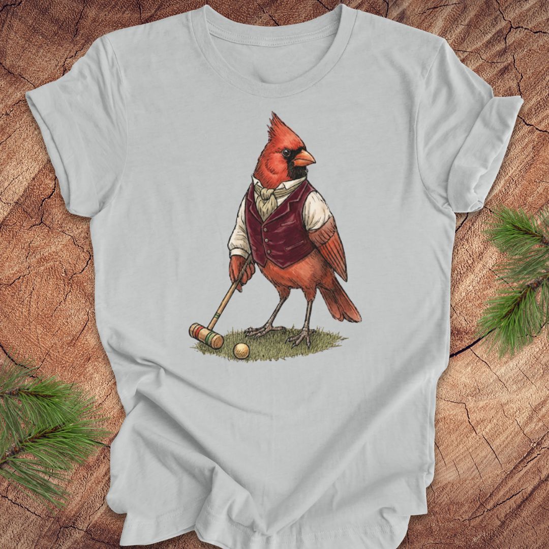 Gray t-shirt with a cardinal playing croquet design on a wooden surface.