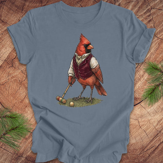 Blue t-shirt with a cardinal playing croquet design on a wooden surface.