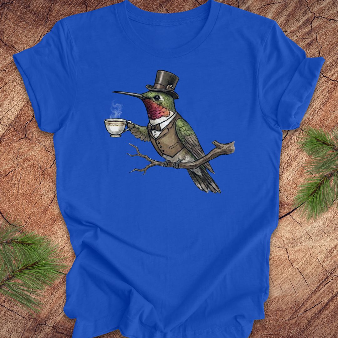 Blue t-shirt with a hummingbird in a top hat holding a tea cup on a wooden surface.