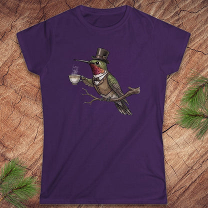 Purple t-shirt with a cartoon hummingbird wearing a top hat and holding a cup on a wooden surface.