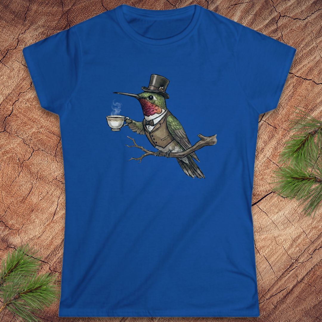 Blue t-shirt with a cartoon hummingbird wearing a top hat and holding a cup on a wooden surface.