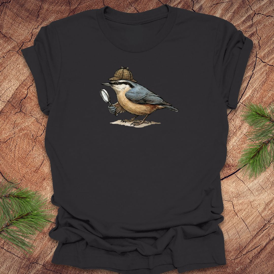 Dark gray t-shirt with a nuthatch bird wearing a sherlock holmes cap and holding a magnifying glass on a wooden surface