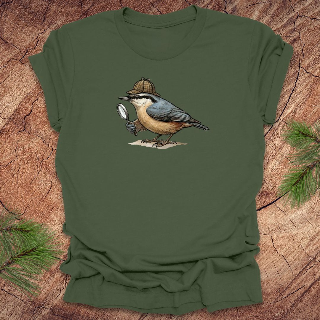 Green t-shirt with a nuthatch bird wearing a sherlock holmes cap and holding a magnifying glass on a wooden surface