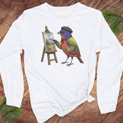White long-sleeve t-shirt with a Painted Bunting in a black beret and red scarf, painting a landscape at a tiny easel, laid flat on a rustic wood background with pine branches.