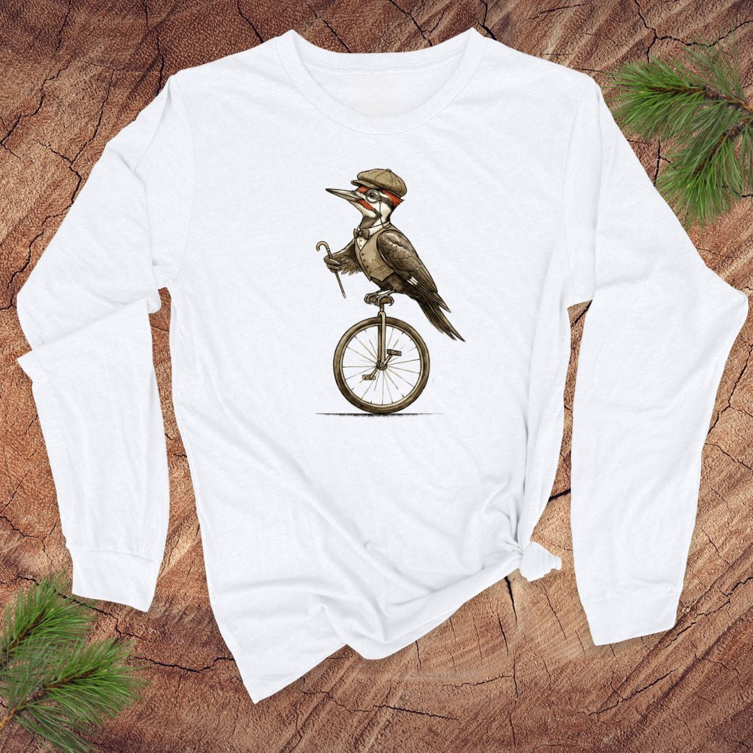 White long-sleeve shirt with a woodpecker on a unicycle design on a wooden surface.