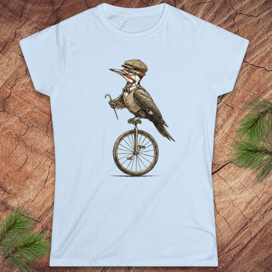 Light blue t-shirt with a woodpecker on a unicycle graphic on a wooden surface.