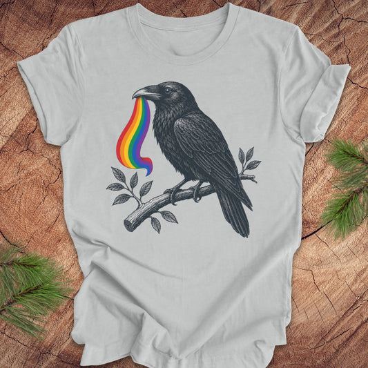 Gray t-shirt with a black crow and rainbow design on a wooden surface.