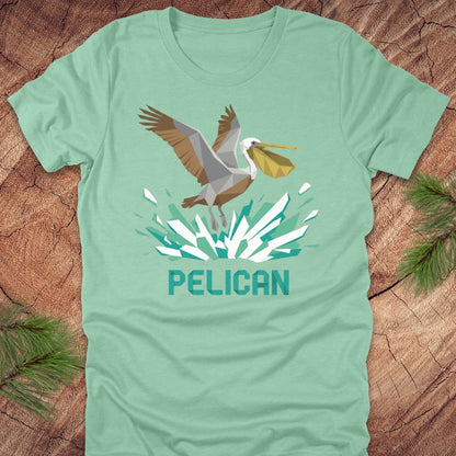 Mint green t-shirt with a pelican graphic and 'PELICAN' text on a wooden surface.