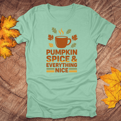 Mint green t-shirt with pumpkin spice and everything nice graphic on a wooden surface with fall leaves.